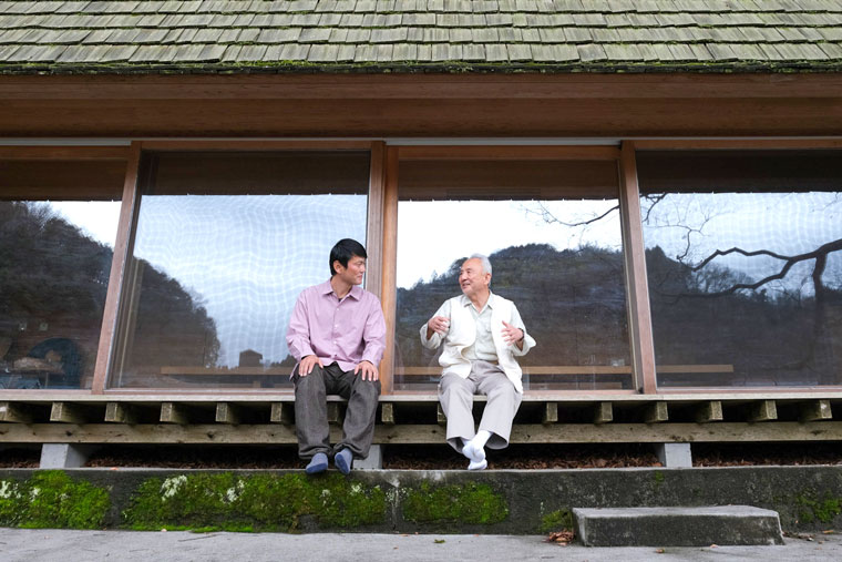 吉野杉の家の縁に座る小川三夫氏と長谷川豪氏